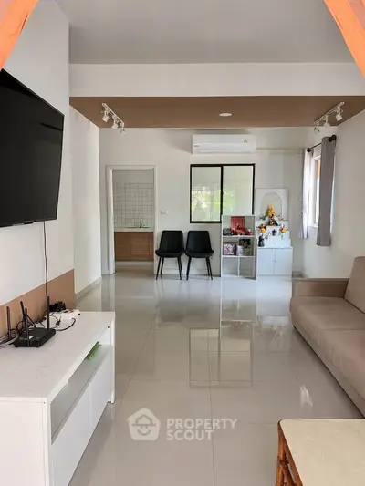 Modern living room with sleek furniture and natural light, featuring a TV and air conditioning.