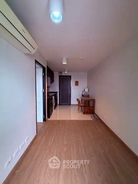 Modern apartment interior with wooden flooring and compact kitchen area.