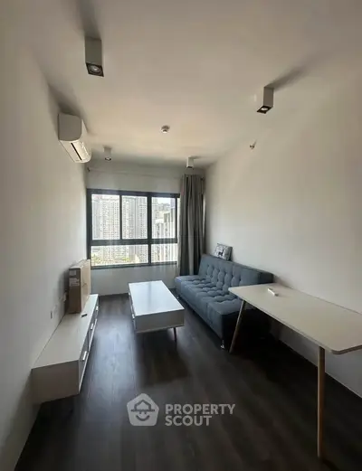 Modern living room with sleek furniture and large window offering city view