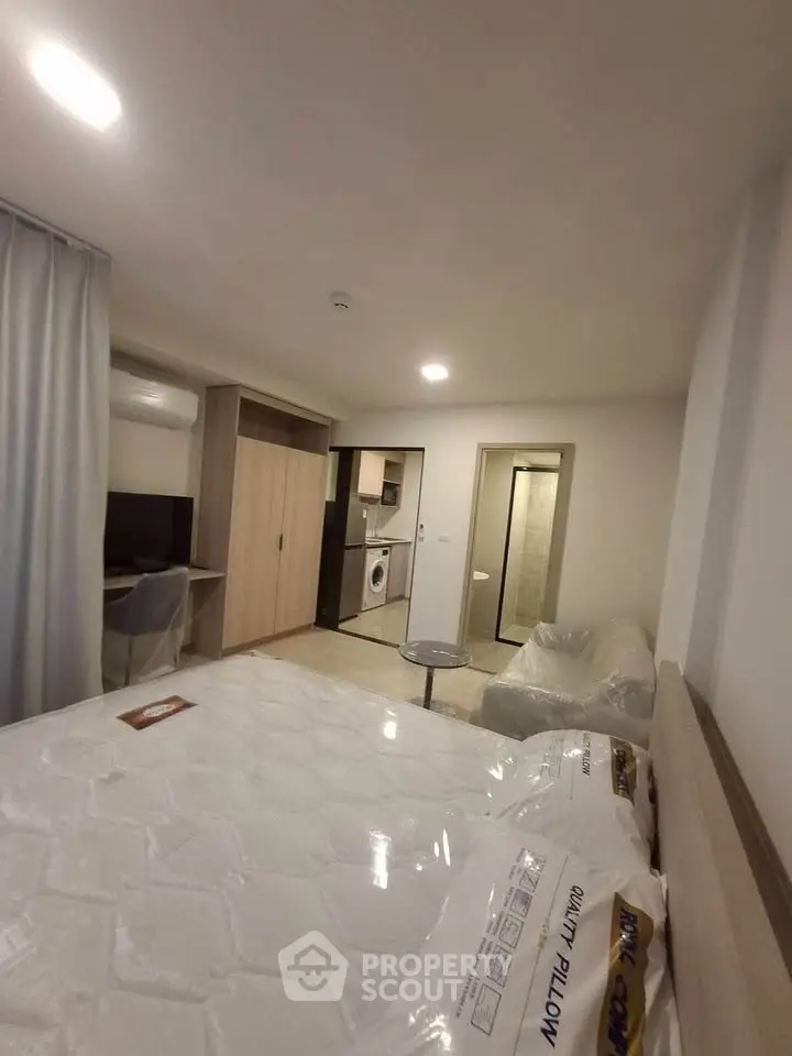 Modern studio apartment with open layout, featuring a cozy living area and in-unit washing machine.