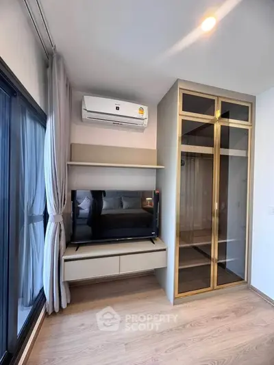 Modern bedroom with sleek wardrobe and wall-mounted TV, featuring elegant wood flooring and air conditioning.