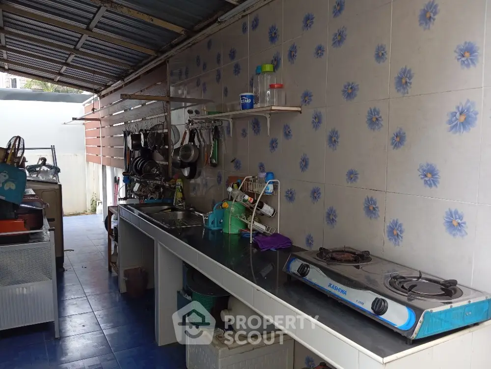Charming outdoor kitchen with gas stove and floral tile backsplash