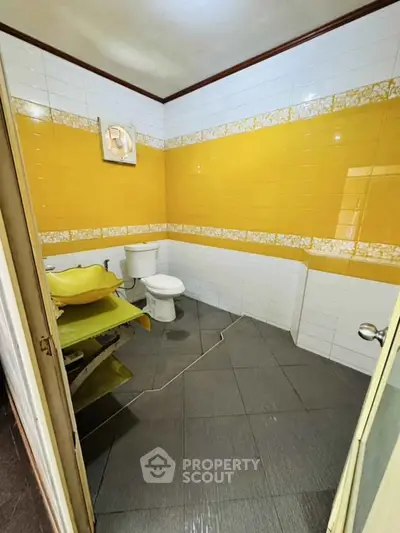 Vibrant yellow-tiled bathroom with modern fixtures and unique design.