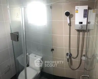 Modern bathroom with glass shower and water heater in sleek tiled design.