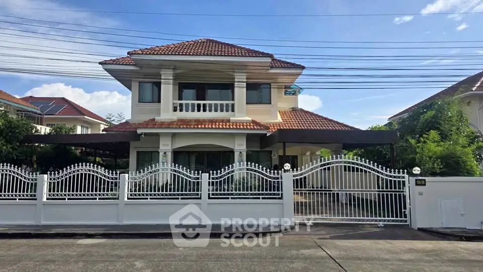 Charming two-story house with red-tiled roof and elegant white fence in a serene neighborhood.