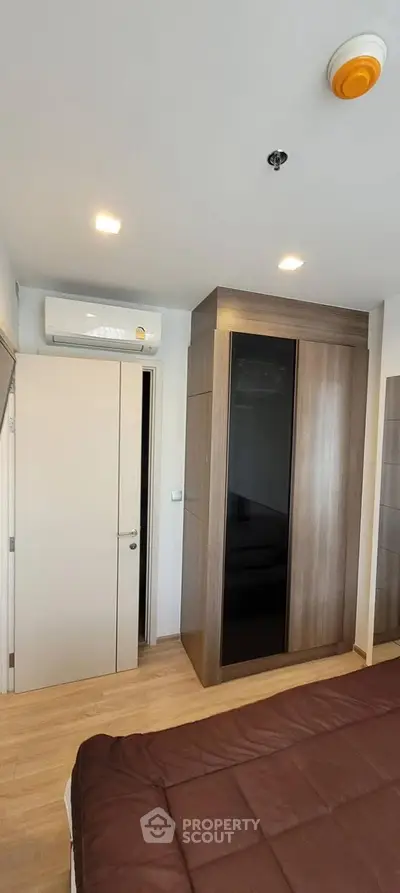 Modern bedroom with sleek wardrobe and air conditioning in a cozy apartment.