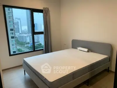 Modern bedroom with large window and city view, featuring a comfortable bed and minimalist decor.