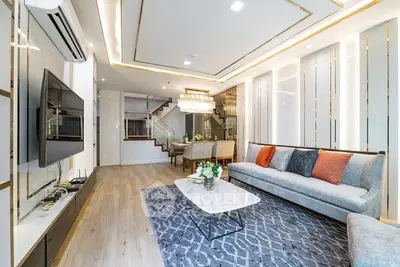 Luxurious modern living room with elegant decor and spacious layout, featuring a stylish staircase and dining area.