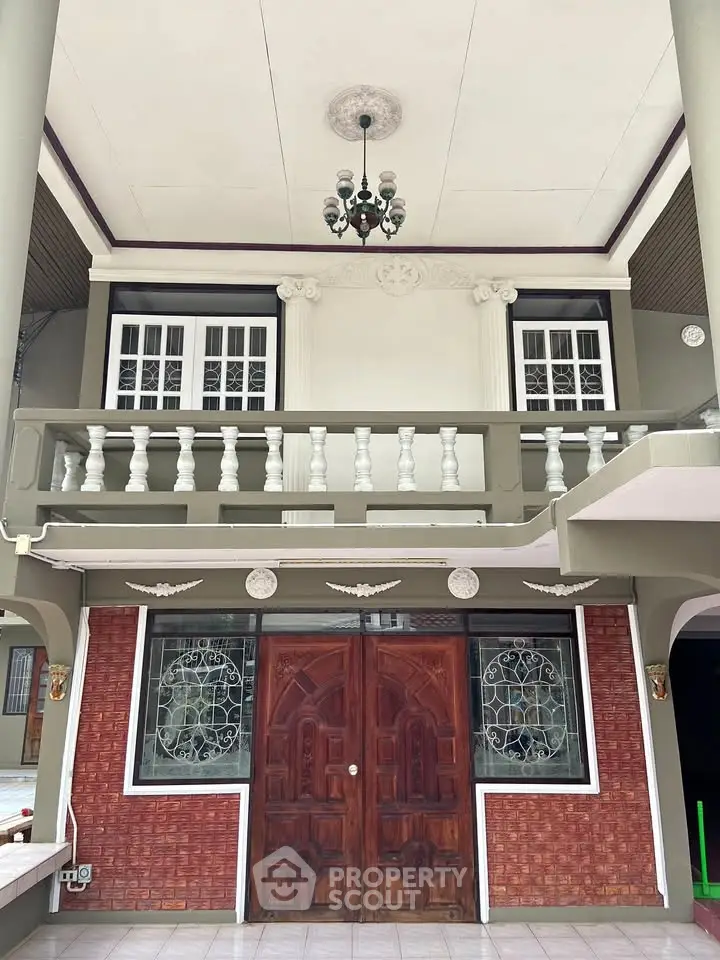Stunning two-story home entrance with elegant balcony and intricate door design.