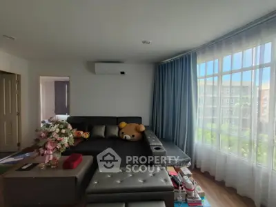 Spacious living room with large windows and modern furniture in a bright apartment.