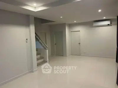 Spacious modern living room with sleek design and staircase, perfect for contemporary living.