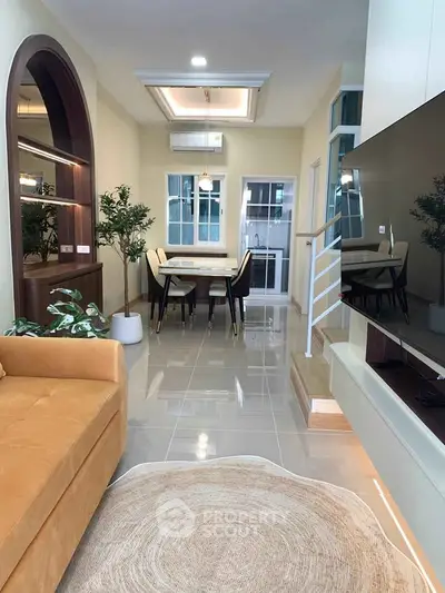 Modern living room with stylish decor and dining area, featuring a cozy sofa and elegant lighting.