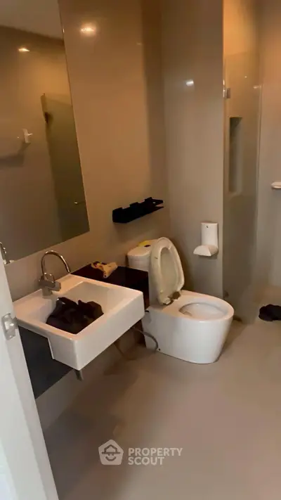 Modern bathroom with sleek fixtures and neutral tones, featuring a compact sink and toilet.
