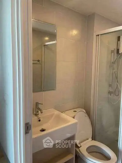 Compact bathroom with modern fixtures and glass shower enclosure in a cozy apartment.