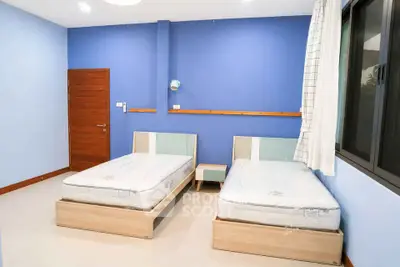 Spacious bedroom with twin beds and modern decor in a serene blue color scheme.