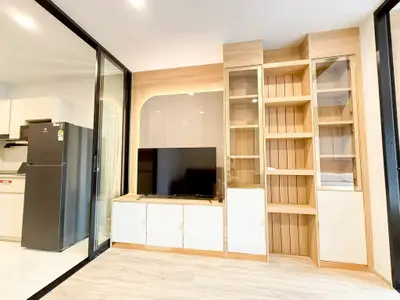 Modern living room with sleek TV unit and glass sliding doors, showcasing contemporary design.