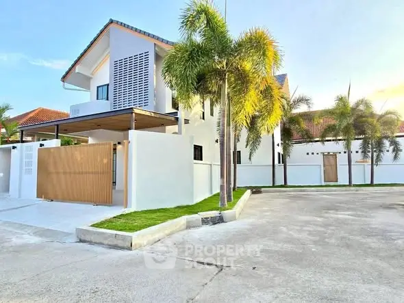 Modern two-story house with palm trees and spacious driveway in a serene neighborhood.