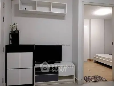 Modern apartment interior with sleek TV unit and cozy bedroom view.