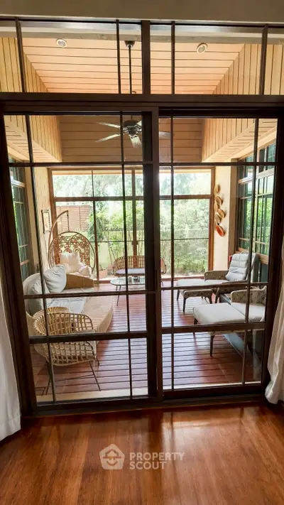 Charming enclosed balcony with cozy seating and lush garden view, perfect for relaxation and entertaining.