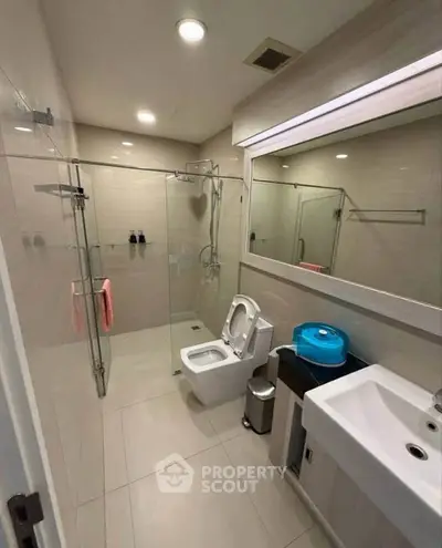 Modern bathroom with glass shower, sleek fixtures, and neutral tiles.