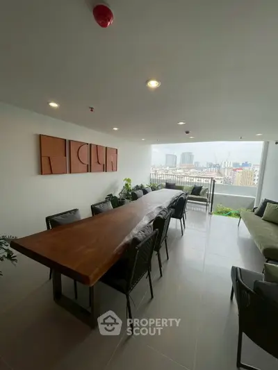 Spacious balcony with city view, featuring a long wooden dining table and modern seating, perfect for entertaining.