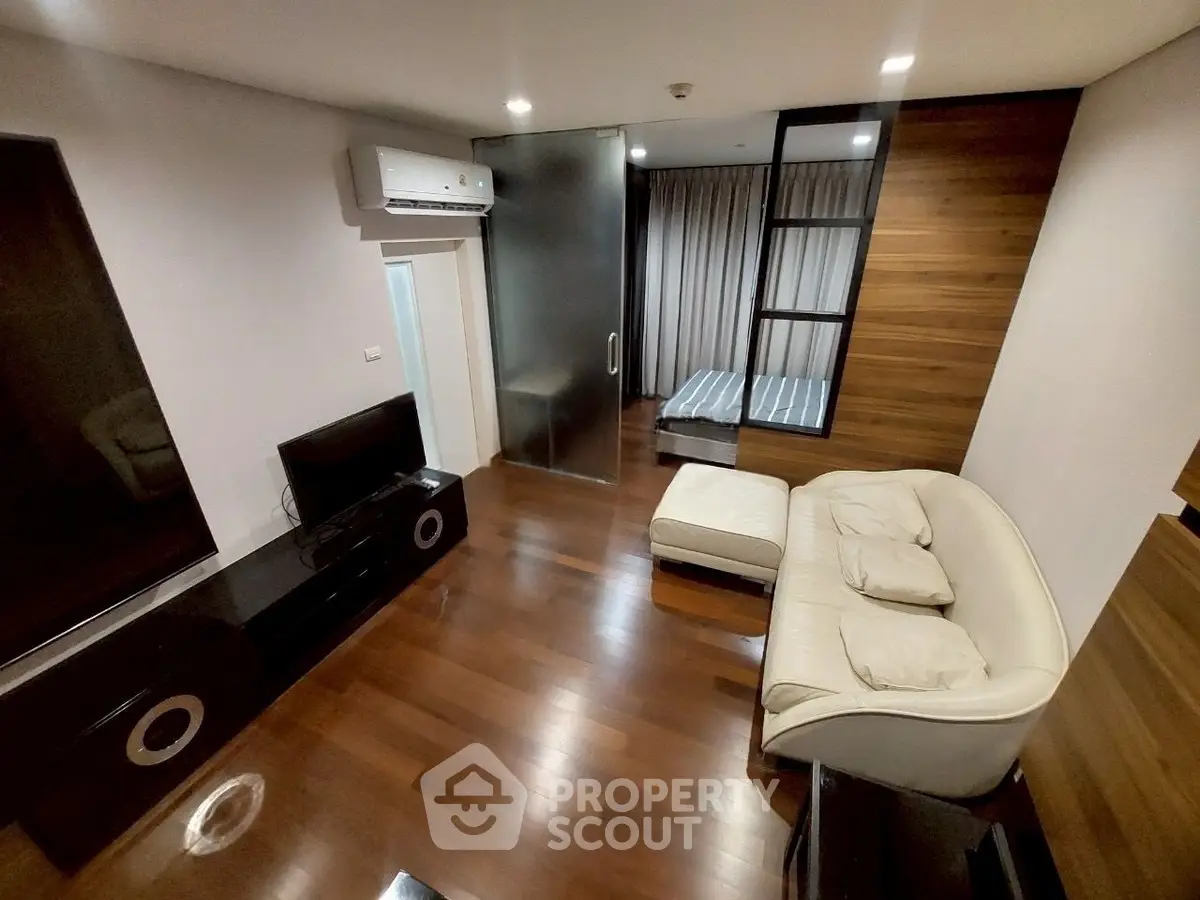 Modern living room with sleek design and wooden flooring, featuring a cozy sofa and entertainment center.