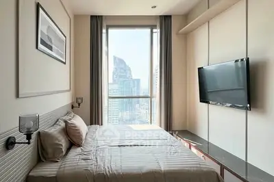 Modern bedroom with city view, featuring a large window and wall-mounted TV, perfect for urban living.