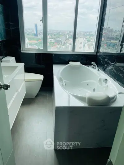 Luxurious bathroom with city view and jacuzzi tub in high-rise apartment.