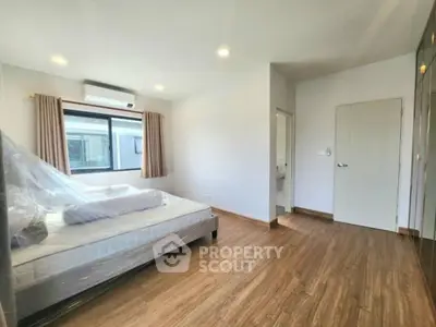 Spacious bedroom with large window and modern wooden flooring