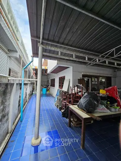 Spacious outdoor area with blue tiled flooring and covered roof, ideal for storage or renovation.