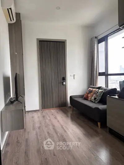 Modern living room with sleek design and city view, featuring a cozy sofa and wall-mounted TV.