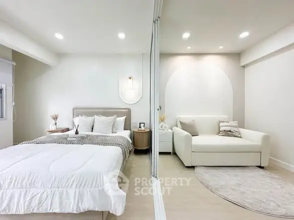 Modern bedroom with cozy living area, featuring elegant decor and neutral tones for a serene ambiance.