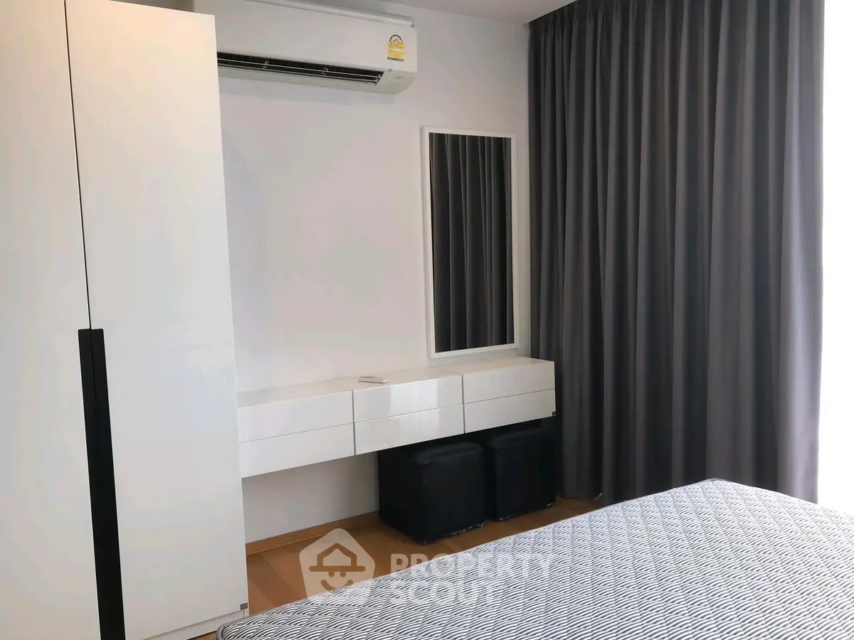 Modern bedroom with sleek furniture and air conditioning, featuring a stylish curtain and mirror.