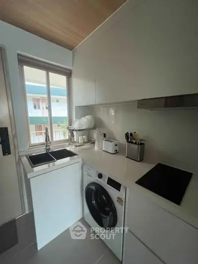 Modern compact kitchen with washing machine and sleek appliances, perfect for urban living.