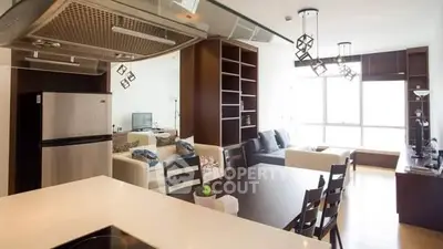 Modern open-layout living room with stylish kitchen and dining area, featuring contemporary furniture and large windows.