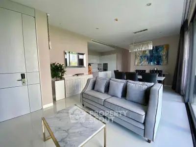 Modern living room with elegant decor and open dining area, featuring a stylish sofa and marble coffee table.