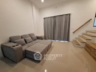 Modern living room with sleek gray sofa and elegant staircase