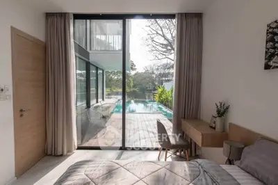 Luxurious bedroom with pool view and modern decor, featuring floor-to-ceiling windows and elegant furnishings.