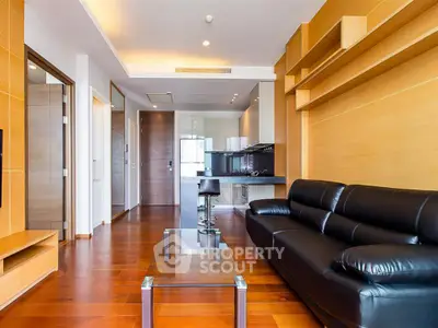 Modern living room with sleek black leather sofa and open kitchen layout