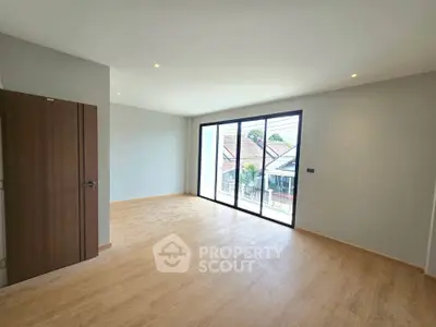 Spacious empty room with large windows and wooden flooring, perfect for customization.