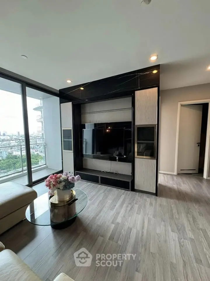 Modern living room with sleek TV unit and city view from large windows.