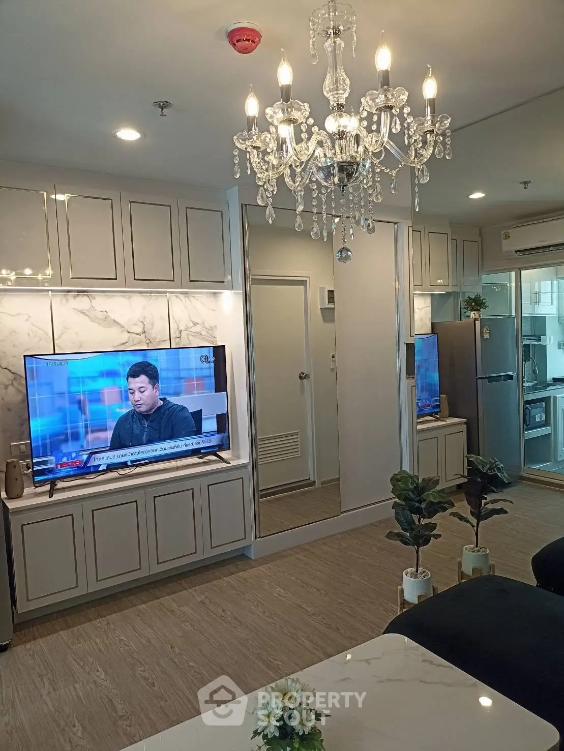 Luxurious living room with chandelier and modern kitchen in open layout apartment