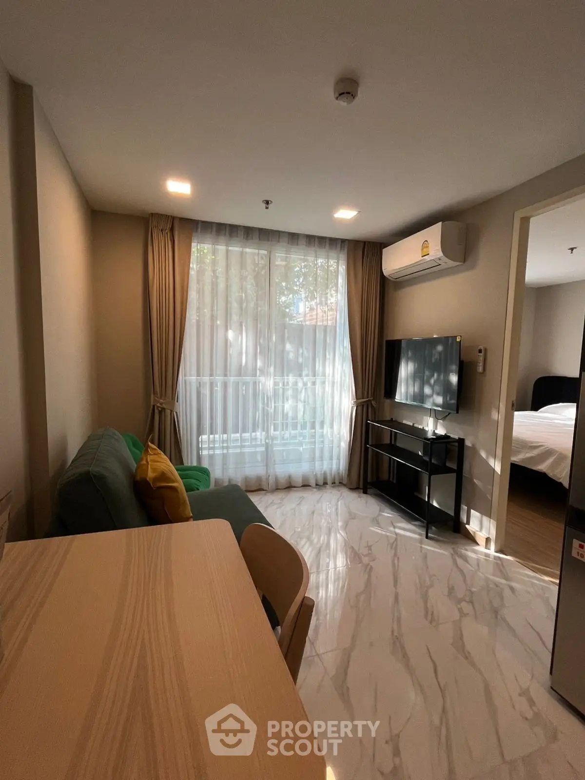 Modern living room with marble flooring and natural light, featuring a cozy sofa and wall-mounted TV.