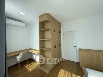 Modern bedroom with built-in wooden wardrobe and study desk, featuring sleek design and natural light.
