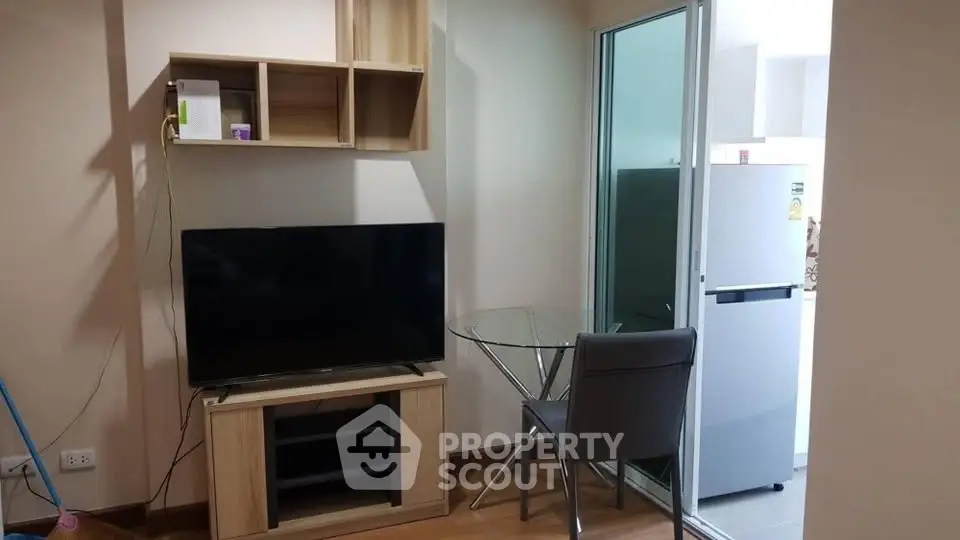 Cozy living room with modern TV setup and glass dining table near kitchen