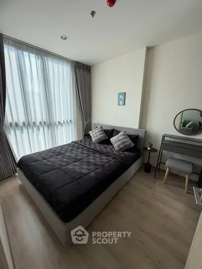 Modern bedroom with large window and stylish decor in a contemporary apartment.
