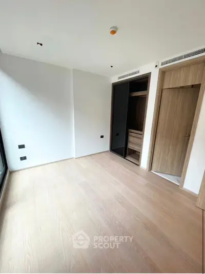 Spacious empty bedroom with wooden flooring and built-in closet, ideal for customization.