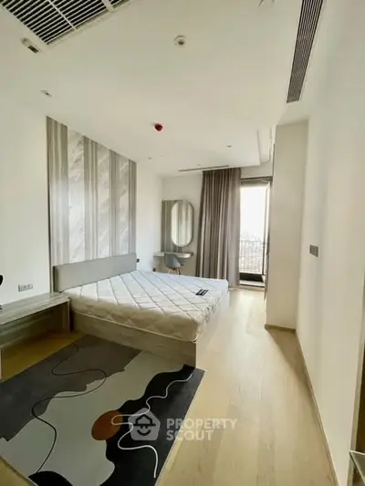 Modern bedroom with stylish decor and balcony access in a contemporary apartment.