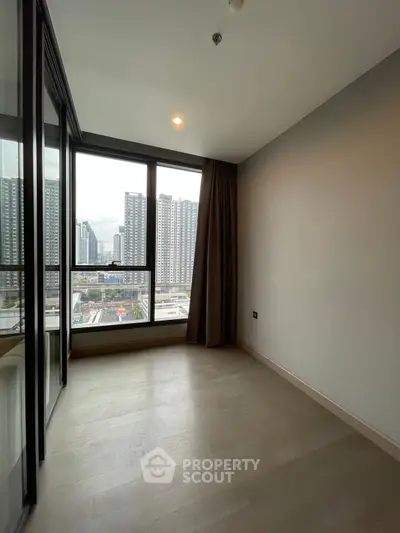 Spacious room with large windows offering stunning city views in modern high-rise building.