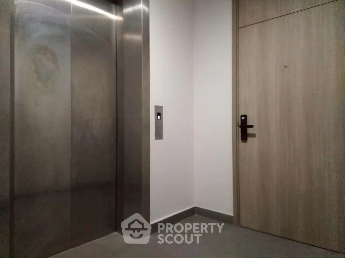 Modern apartment elevator and entrance door in a sleek hallway.